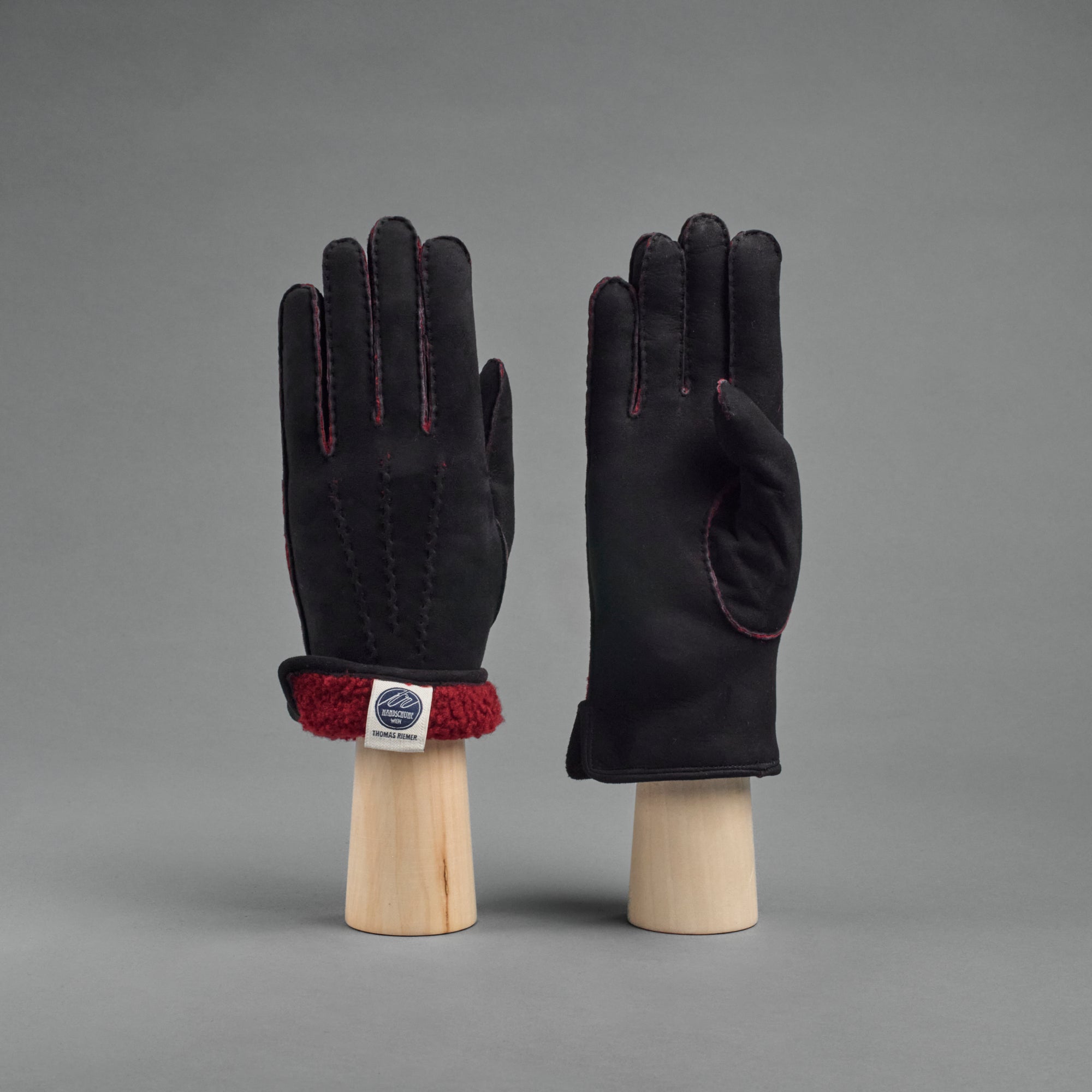 Damenhandschuhe aus schwarzem gelocktem Lammfell mit rotem Futter